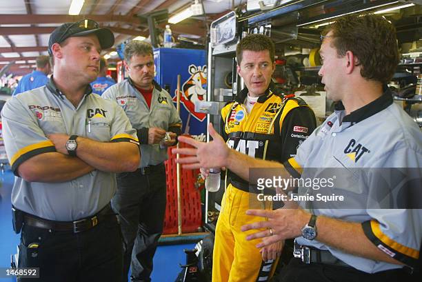 Ward Burton, driver of the Bill Davis Racing Dodge Intrepid R/T, talks with crew members during practice for the EA Sports 500 at Talladega...