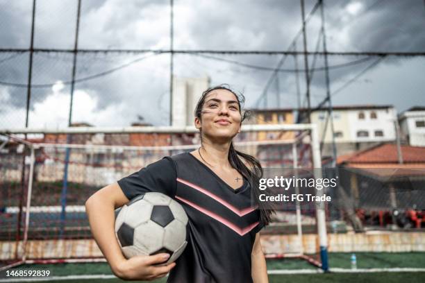 jugadora de fútbol mirando hacia otro lado contemplando en el campo - fútbol femenino fotografías e imágenes de stock