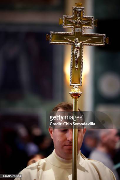 With a cross of ash on his forehead, a crucifer leads the recession during an Ash Wednesday Mass at the Cathedral of St. Matthew the Apostle on...
