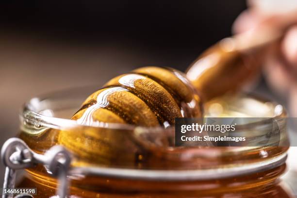 healthy organic thick honey dipping from the wooden honey spoon, closeup. - syrup stockfoto's en -beelden