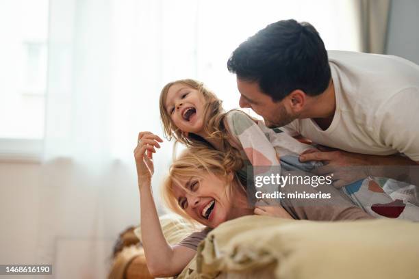 happy family in sleepwear having fun together in the bedroom - horizontaal stockfoto's en -beelden