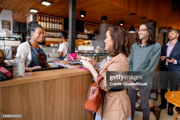 businesswoman paying her bill at coffee shop checkout - coffee shop owner stockfoto's en -beelden