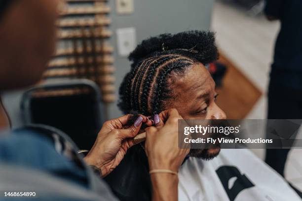 man having hair braided in barber shop - african american hair salon stock pictures, royalty-free photos & images