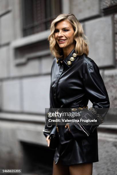 Martina Colombari is seen wearing a black, studded leather jacket embroidered with rhinestone and a belt with gold triangular embellishment outside...