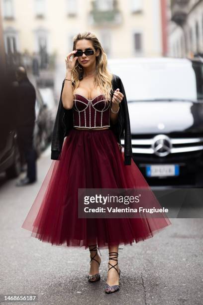 Michela Persico is seen wearing black Balenciaga sunglasses, a black leather jackets, a burgundy corset embroidered with rhinestones, a burgundy lace...