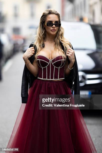 Michela Persico is seen wearing black Balenciaga sunglasses, a black leather jackets, a burgundy corset embroidered with rhinestones, a burgundy lace...