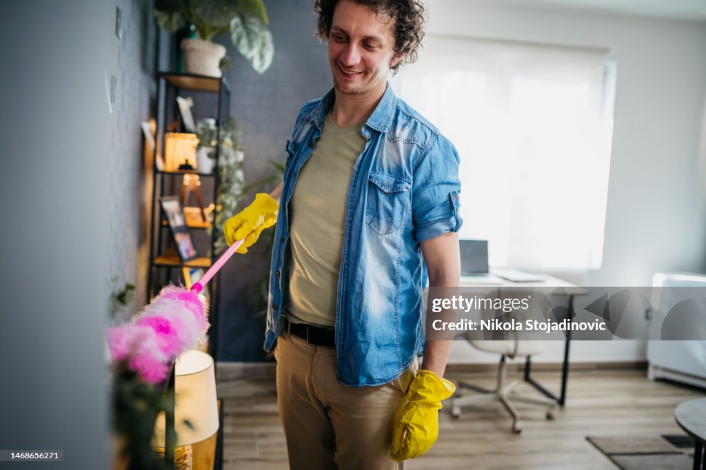 Junger Mann mit einem Staubtuch Reinigung
