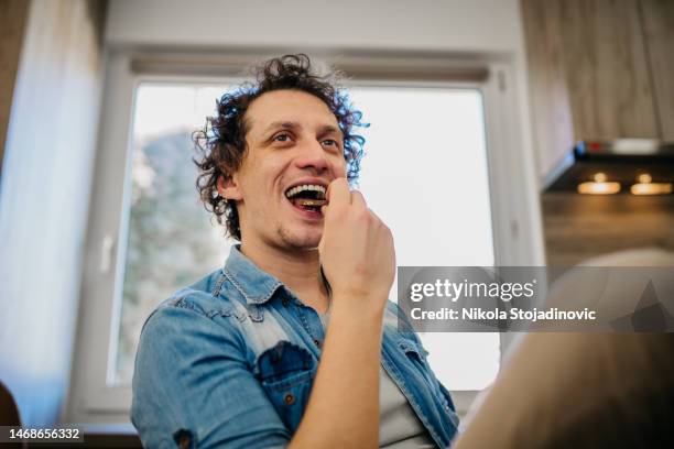 young handsome man eating chocolate bar - chocolate eating stock pictures, royalty-free photos & images