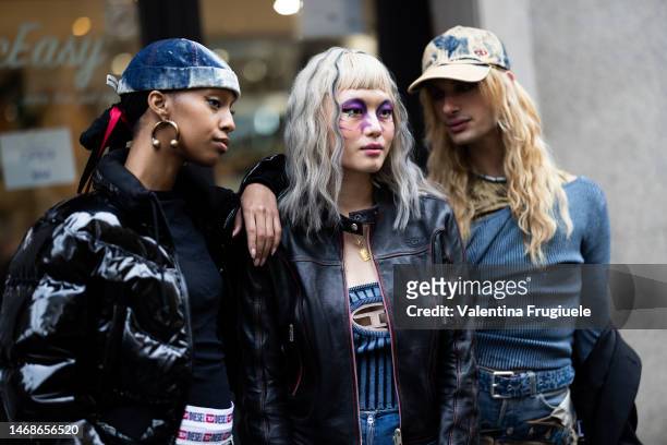 Houdan Yousuf is seen wearing gold circle earrings, a Diesel white and blue tie-dye hat, a black shiny puffy, cropped, vinyl winter jacket, a...
