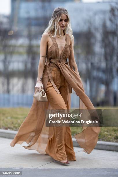 Victoria Magrath is seen wearing a slit chiffon brown dress over orange wide chiffon pants, gold bag and gold neckless outside the Alberta Ferretti...