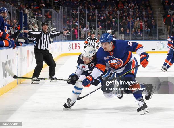 Ryan Pulock of the New York Islanders and Mason Appleton of the Winnipeg Jets battle for the puck during the first period at the UBS Arena on...