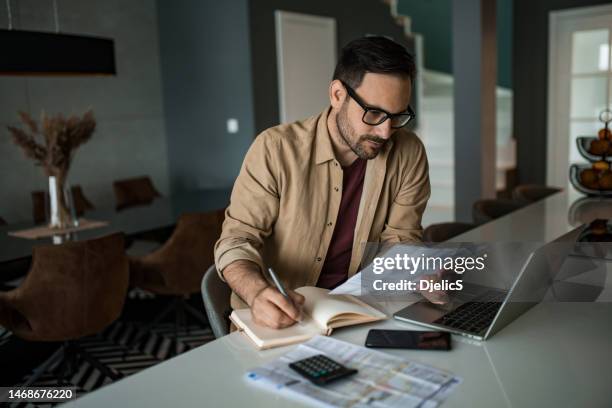 junger mann, der zu hause an finanzrechnungen und steuern arbeitet. - mittelalter mann stock-fotos und bilder