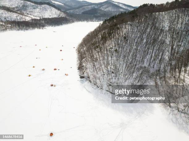 High angle drone view of frozen lake with lots of tents of people ice fishing