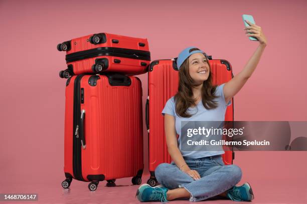 young female traveler taking a picture with her suitcases, sitting on the floor - sitting and using smartphone studio stock pictures, royalty-free photos & images