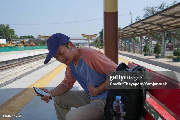 asian men stomach ache while traveling at rail way station. - appendicitis stock pictures, royalty-free photos & images