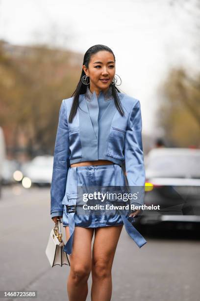 Yuwei Zhangzou wears silver logo pendant earrings from Fendi , a blue silk shoulder-pads / cropped jacket from Fendi, a matching pale blue silk cargo...