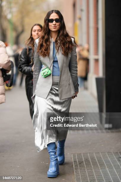 Erika Boldrin wears black sunglasses, a blue t-shirt, a pale gray with silk sleeves blazer jacket from Fendi, a gray silver silk midi skirt from...