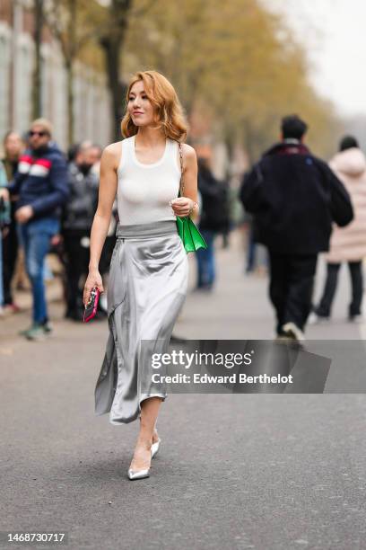 Guest wears a white tank-top, a neon green shiny varnished leather shoulder bag from Fendi, a silver gray silk midi dress, silver shiny leather...