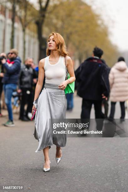 Guest wears a white tank-top, a neon green shiny varnished leather shoulder bag from Fendi, a silver gray silk midi dress, silver shiny leather...