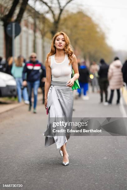 Guest wears a white tank-top, a neon green shiny varnished leather shoulder bag from Fendi, a silver gray silk midi dress, silver shiny leather...