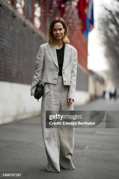 Guest wears a black t-shirt, a pale gray linen cropped blazer jacket, matching pale gray linen large suit pants, a black shiny leather braided puffy...