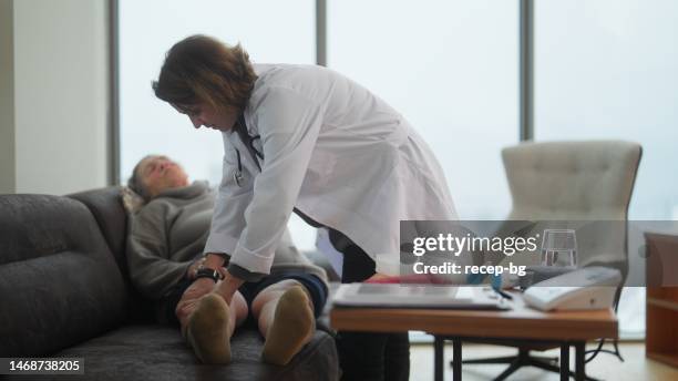 female doctor visiting female senior patient at home and checking her swollen legs - blood flow stock pictures, royalty-free photos & images