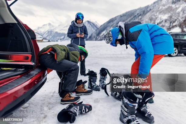 family putting on ski gear before skiing in european alps - ski boot stock pictures, royalty-free photos & images