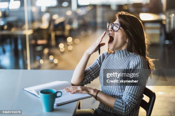 esausta segretaria donna sbadigliando in ufficio. - yawning foto e immagini stock