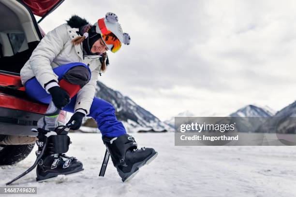 teenage girl putting on ski gear before skiing in european alps - skischoen stockfoto's en -beelden