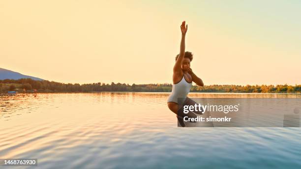 woman jumping in lake - escapism stock pictures, royalty-free photos & images