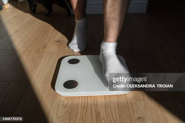 mid adult man step on weight scales at home - schlank stock-fotos und bilder