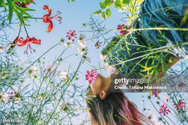 defocused woman with long hair in flowers view from below. - 花　青 ストックフォトと画像