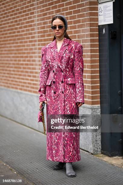 Guest wears a pale gray wool hoodie / balaclava, black sunglasses, a red with black and white print pattern buttoned long blazer coat, a pink shiny...