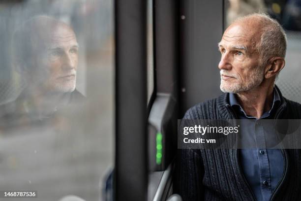 senior adult man riding bus and looking in window - constituency stock pictures, royalty-free photos & images