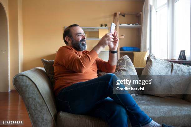 a man with a cell phone at home - scrolling stock pictures, royalty-free photos & images