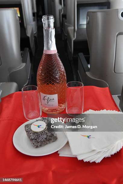 Bottle of Kylie Minogue prosecco beside a rainbow lamington cake onboard flight QF18 from LAX International Airport to Sydney on February 22, 2023 in...