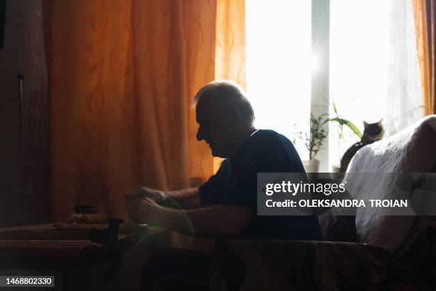 old man eating at home in living room - solitario foto e immagini stock