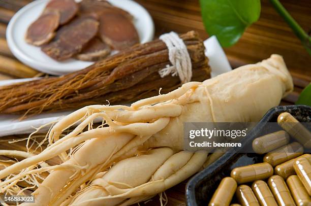 close-up of dry ginseng slices, capsules and roots - ginseng stockfoto's en -beelden