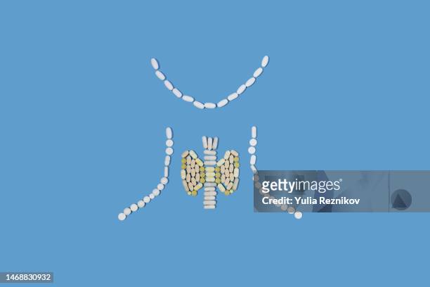 pills in shape of human thyroid gland on the blue background - thyroid gland stock-fotos und bilder