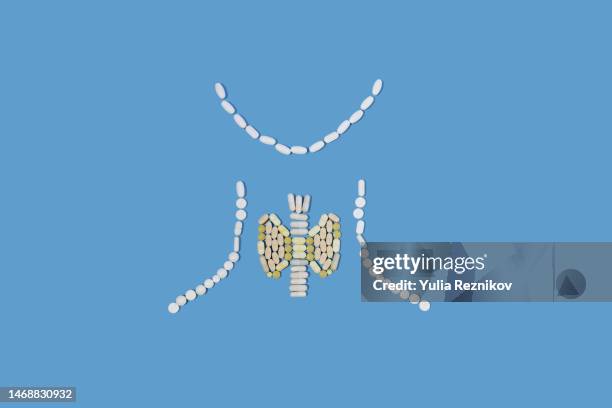 pills in shape of human thyroid gland on the blue background - sköldkörtel bildbanksfoton och bilder