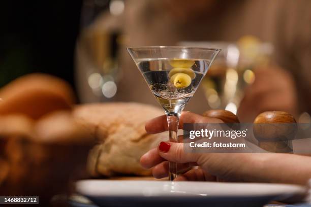 femme dégustant un martini aux olives vertes lors d’un dîner avec des amis - martini dry photos et images de collection