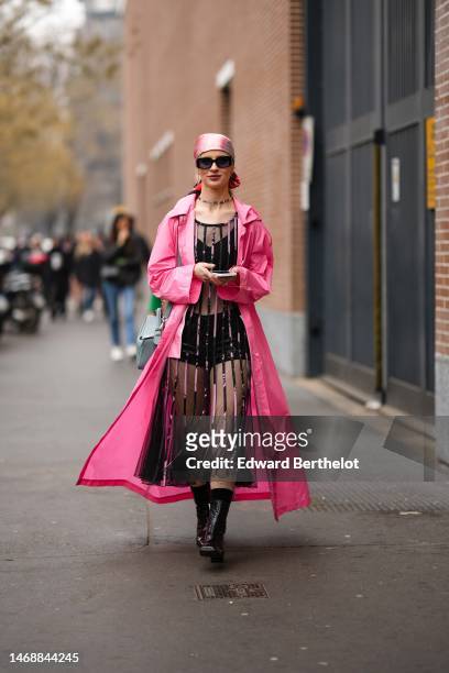 Guest wears a pale pink satin silk scarf as a headband, black sunglasses, a black tulle transparent with embroidered velvet striped pattern long...