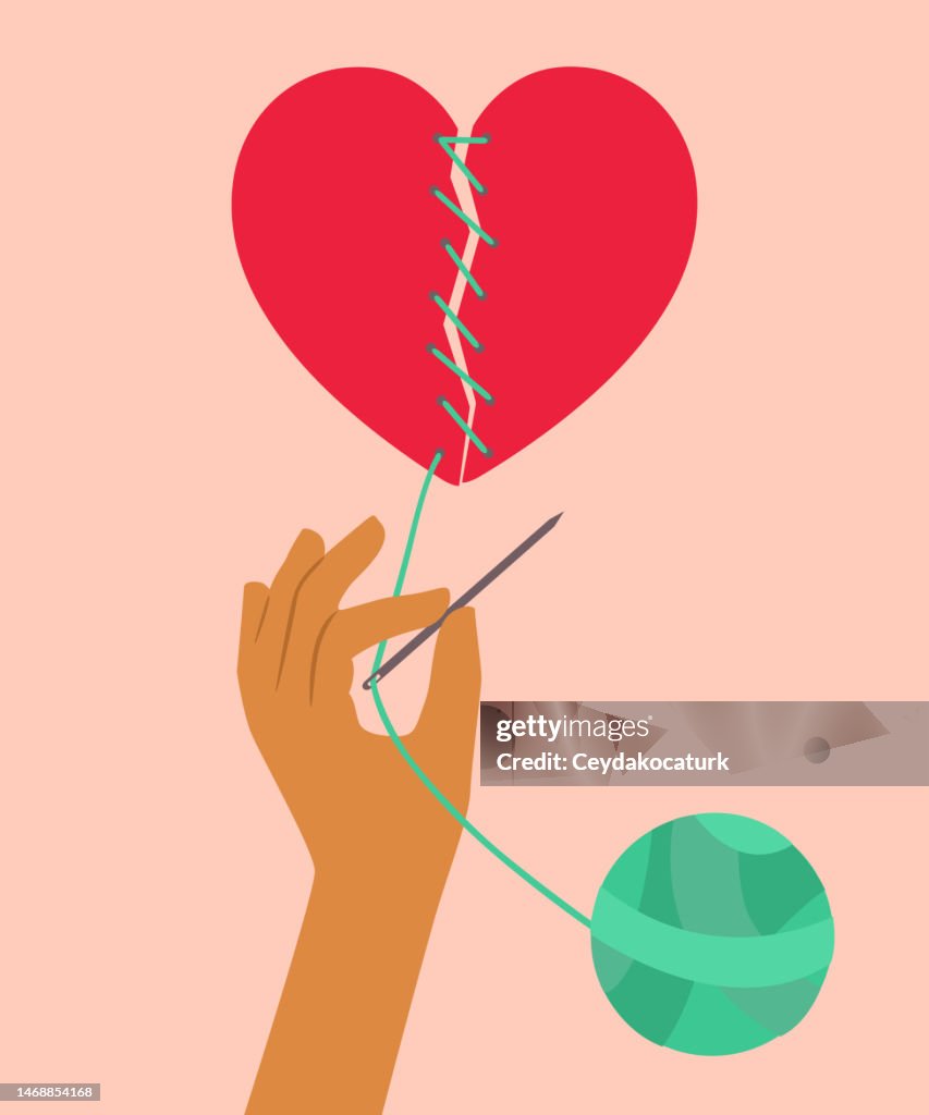 Hand trying to mend a broken heart by sewing