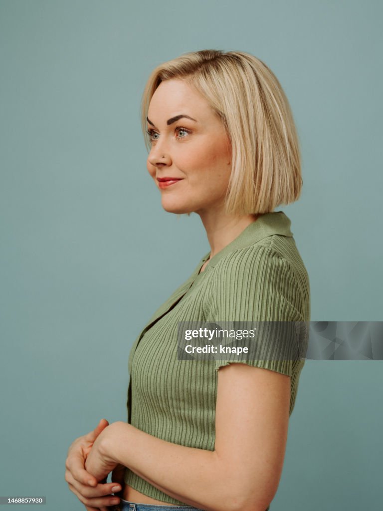 Einfaches Porträt einer mittelerwachsenen Frau in ihren 40ern mit einem kurzen blonden Bob in Freizeitkleidung