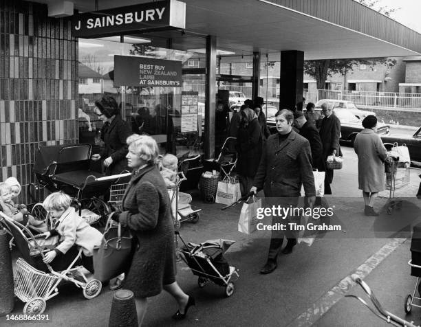 Shoppers pushing supermarket trolleys and carrying shopping bags outside the J Sainsbury's supermarket, in Sutton, London, England, 10th April 1970....