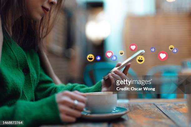 young woman receiving notifications from social media platform on smartphone at cafe - social media marketing stock pictures, royalty-free photos & images