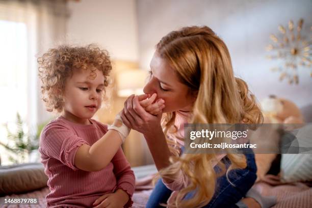 une jeune mère panse la main de sa fille blessée - wounded photos et images de collection