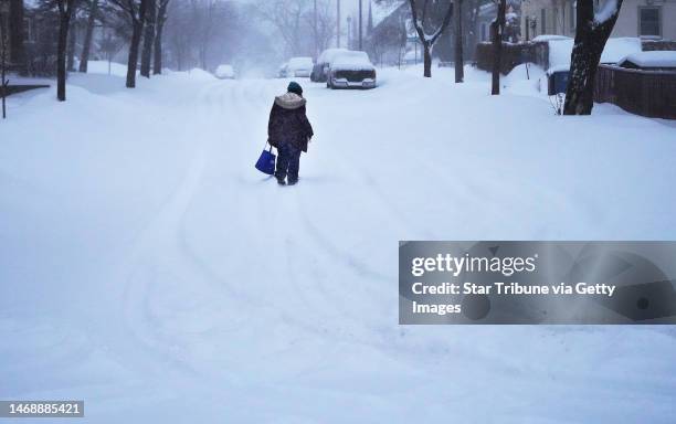 Pedestrian walks in the street along E. 41st St. Near Portland Ave. S. During the third consecutive day of snowfall on the city's south side...