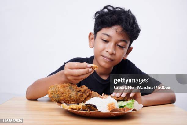 boy eating food at table against white background,bali,indonesia - heri mardinal stock pictures, royalty-free photos & images