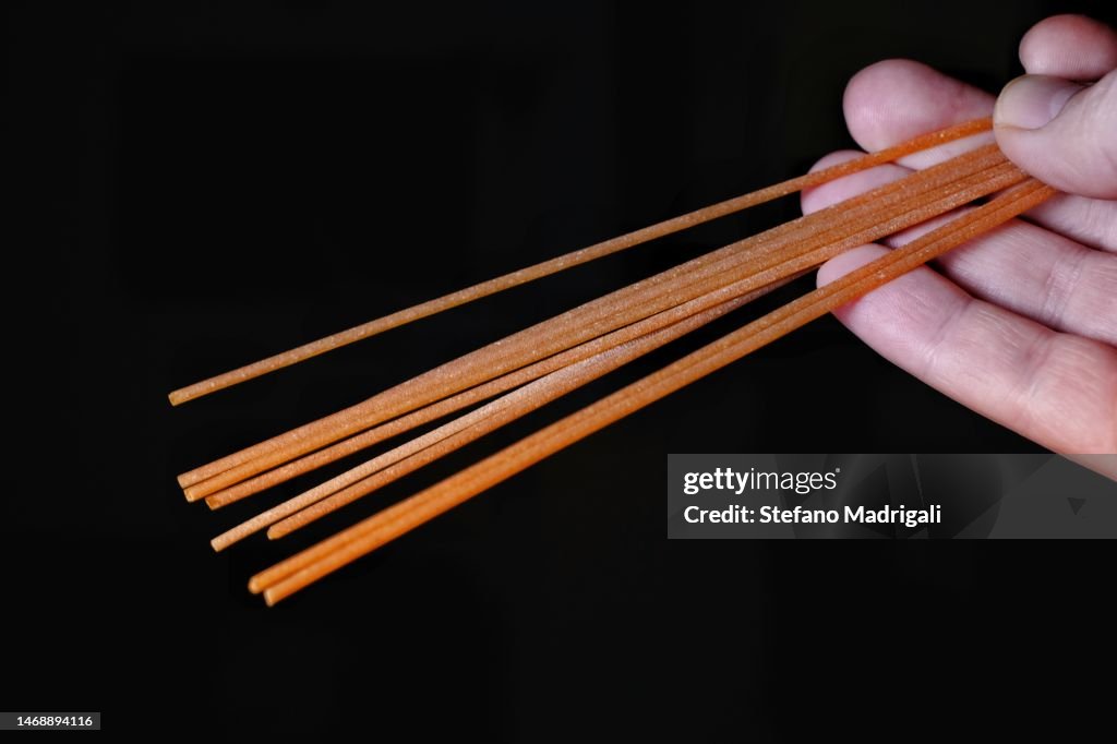 Hand-held dried spaghetti, black background